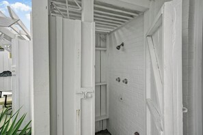 Eine weiße Holzkonstruktion mit einer Tür, einem Fenster und einer kleinen Stufe, die zu einer unteren Ebene führt.