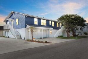A two-story residential house with a front porch, a garage, and a tree in the front yard. - Fire Pit | Pet-Friendly | 2 Blocks to Pier (Kure Beach)
