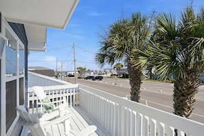 A balcony with white railings, a white chair, and a palm tree. - Fire Pit | Pet-Friendly | 2 Blocks to Pier (Kure Beach)