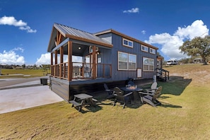 A two-story house with a covered porch, a fire pit, and outdoor seating. - Luxury Tiny Home Hideaway with Resort-Style Amenities Near Fredericksburg, TX (Fredericksburg)