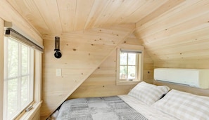 A wooden cabin room with a bed, a window, and an air conditioning unit. - Luminous Tree House with Hot-tub in Gatlinburg, Tennessee (Gatlinburg)