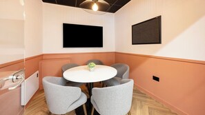 A conference room with a white table, four grey chairs, a small plant, and two black screens on the walls. - Student Only Curzon House (Nottingham)