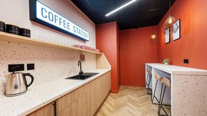 Eine Küchenzeile mit Kaffeestation, Wasserkocher und Barhocker.
