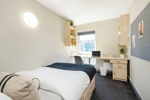 A hotel room with a bed, desk, chair, and a small window. - Student Only Curzon House (Nottingham)
