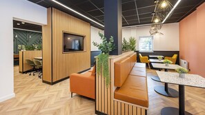 An office space with a modern design, featuring a wooden partition, a television, seating areas, and a dining table with chairs. - Student Only Curzon House (Nottingham)