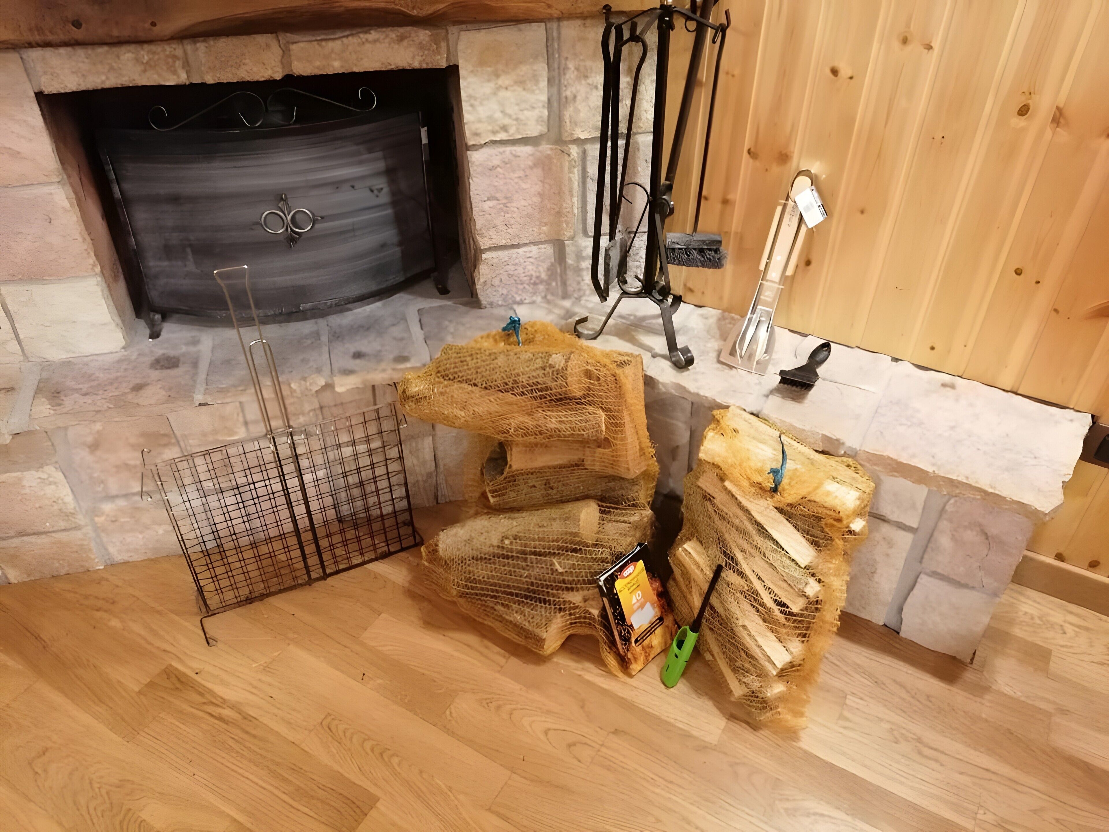 A fireplace with a stone surround, a metal fire screen, and a wooden floor.