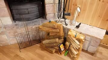 A fireplace with a stone surround, a metal fire screen, and a wooden floor.