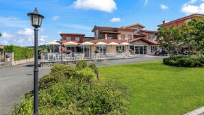 A hotel with outdoor seating, a paved entrance, and a well-maintained lawn. - Villa Carolina Rooms (Castelletto d'Orba)
