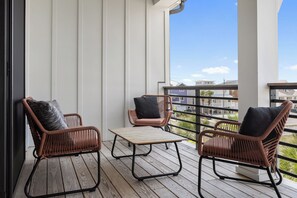 A balcony with wicker chairs and a table, overlooking a residential area. - 4BR Beach Home | Pet Friendly | Walk to Ocean (Kure Beach)