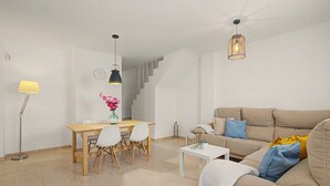 Ein modernes Wohnzimmer mit einer Couch, einem Esstisch mit Stühlen, einem Couchtisch und einer Treppe.