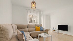 Ein modernes Wohnzimmer mit einem beigen Sofa, einem weißen Couchtisch und einem Flachbildfernseher auf einem Lowboard.