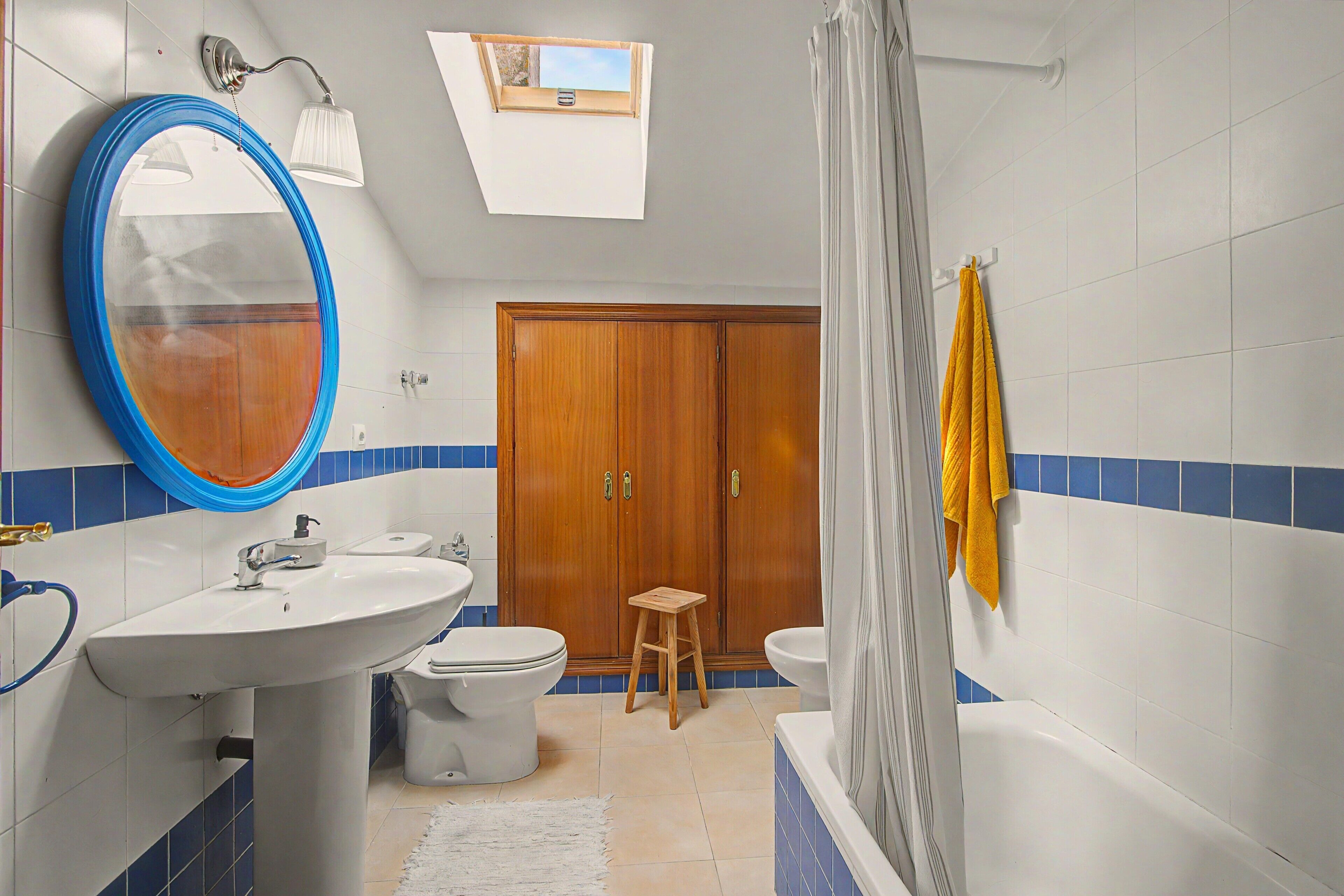 Een badkamer met een houten garderobe, een witte wastafel, een toilet en een bad.