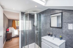 A modern bathroom with a glass-enclosed shower, a white sink, and a large mirror. - Pet Friendly Family Home in New Cross with Garden (Greater London)
