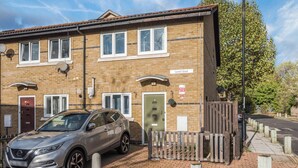 A two-story brick building with a car parked in front, a wooden fence, and a street sign indicating 'Liardet Street'. - Pet Friendly Family Home in New Cross with Garden (Greater London)