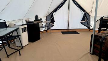 A tent interior with a table, a heater, and a sleeping area.