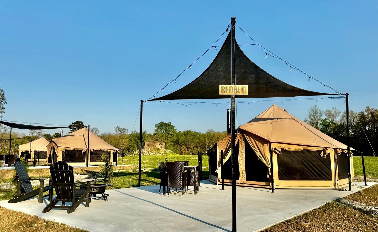 A campsite with tents, a table, chairs, and a sign.