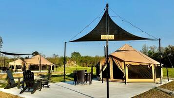 A campsite with tents, a table, chairs, and a sign.