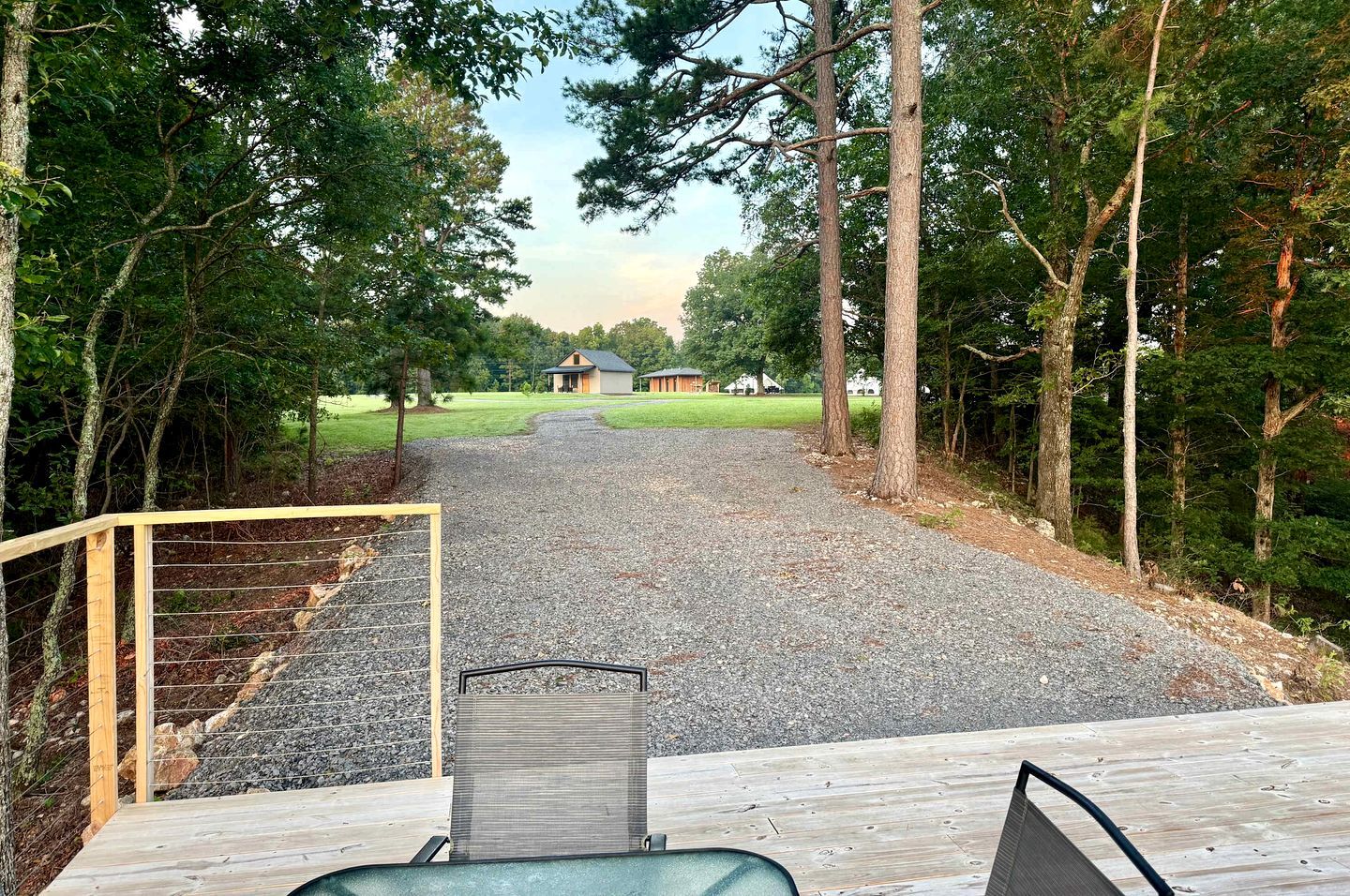 A gravel driveway leading to a house with a wooden deck in the foreground.