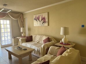 A cozy living room with a sofa, a coffee table, and two lamps. - Charming 2-bedroom apartment in a St James, Barbados 5 mins from the beach. (Saint James)