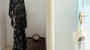 Una stanza con una panca bianca, un capo di abbigliamento appeso, una borsa a stampa leopardo e un paio di scarpe.