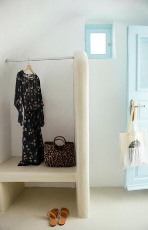 Ein Zimmer mit einer weißen Bank, einem aufgehängten Kleidungsstück, einer Leopardenmuster-Tasche und einem Schuhpaar.
