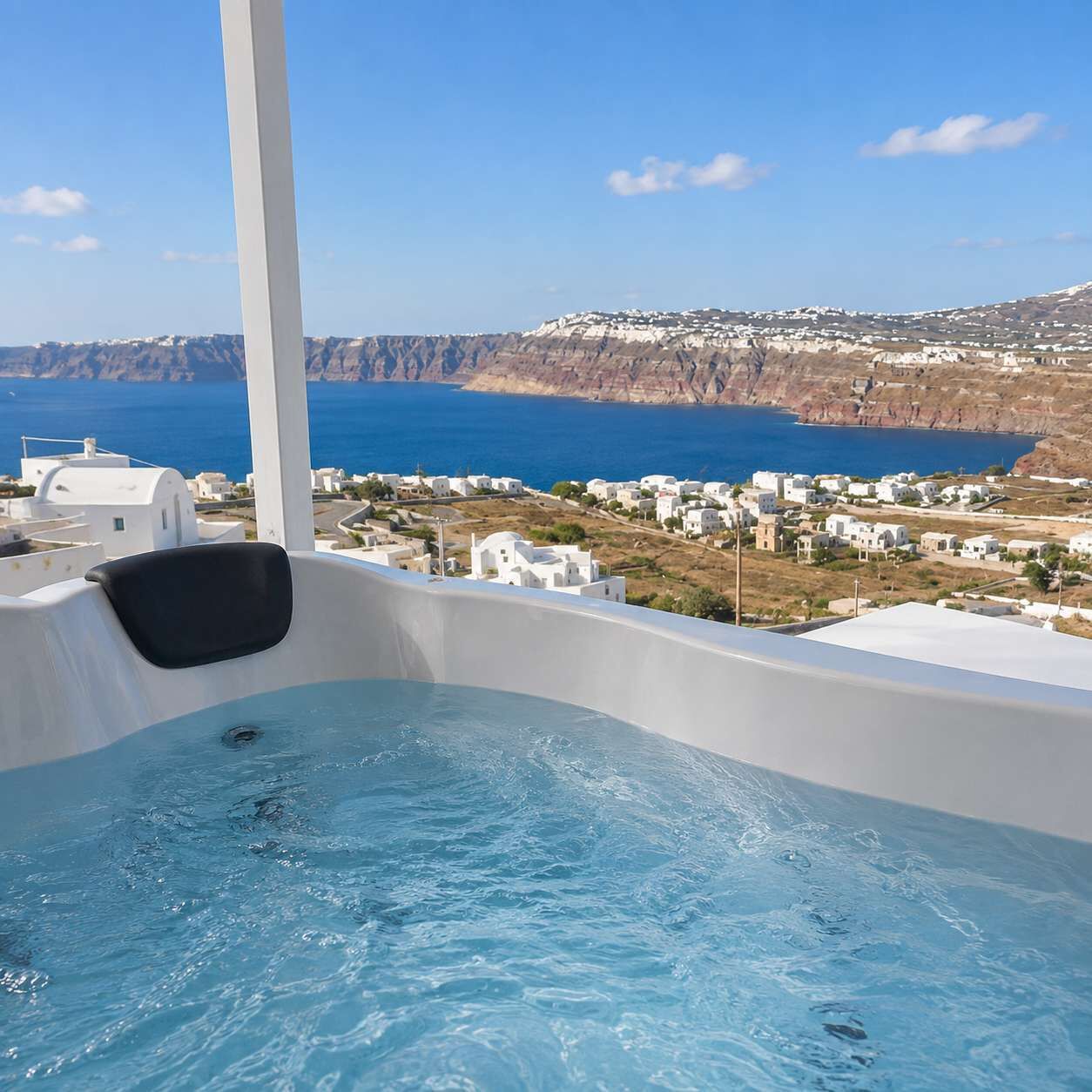 A hot tub with a view of a coastal town and cliffs.