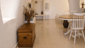 Um interior moderno com uma mesa de jantar redonda, cadeiras brancas, um baú de madeira e um banco.