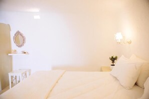Ein schlicht eingerichtetes Schlafzimmer mit Bett, Nachttisch, Lampe und einer kleinen Topfpflanze.