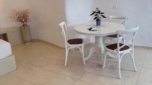 Ein Essbereich mit einem runden Tisch, vier Stühlen, einer Vase mit Blumen und einer strukturierten Wand.