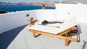 Eine Liege auf einer Dachterrasse mit Blick auf das Meer und die Klippen.