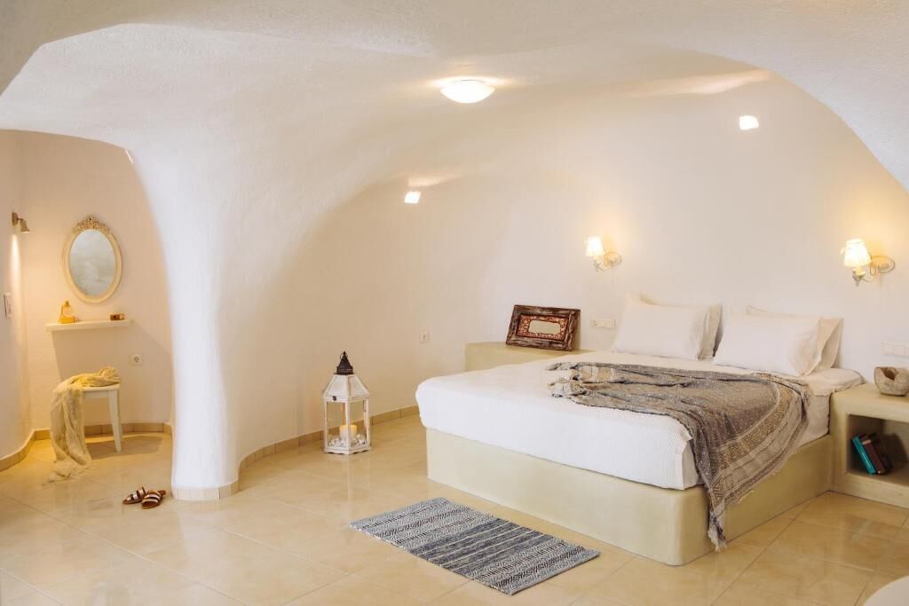 Une chambre à coucher avec un plafond incurvé, un lit, une table de chevet, une lampe et un miroir.