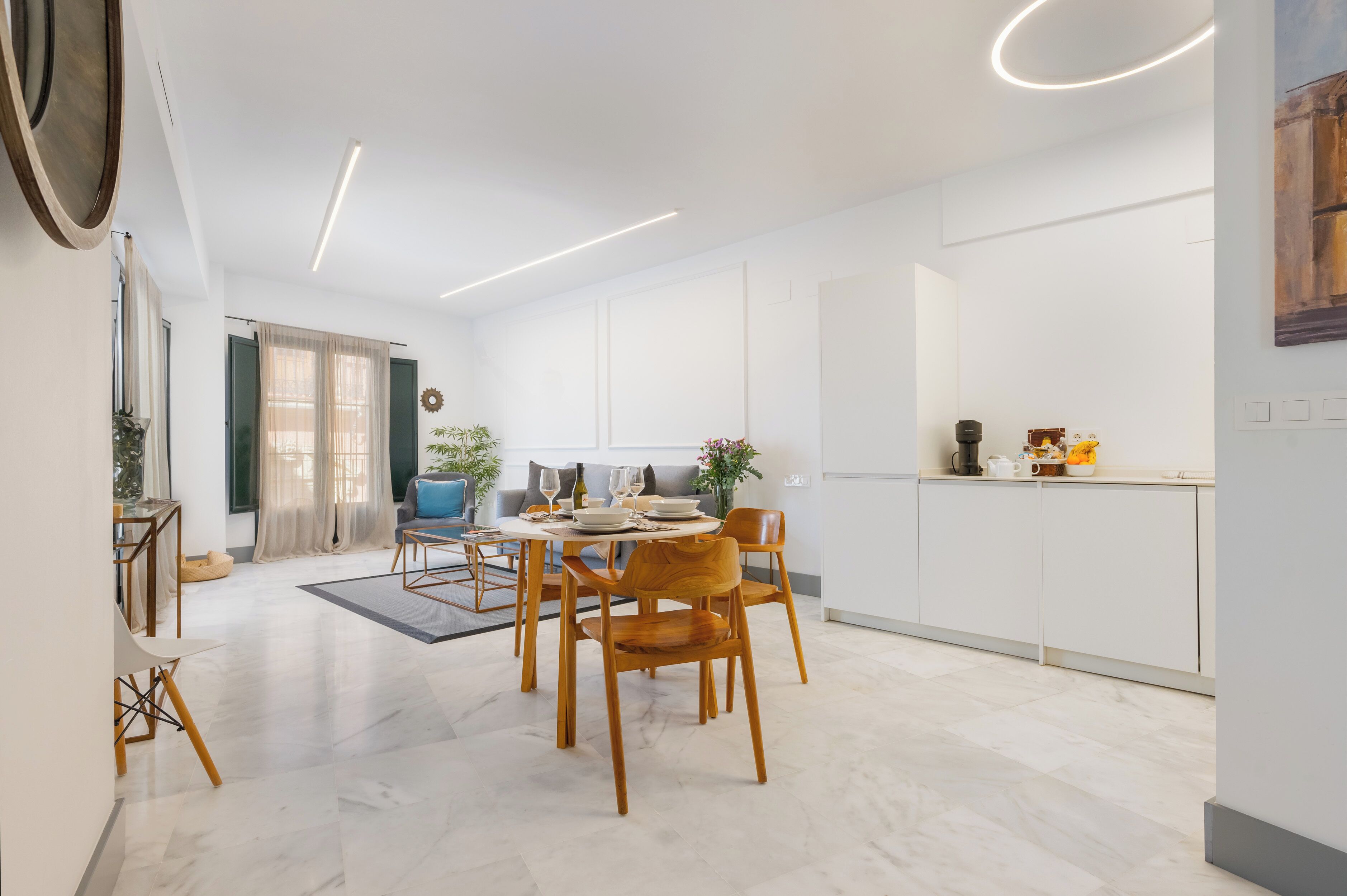 A modern dining area with a round table, wooden chairs, and a sofa.