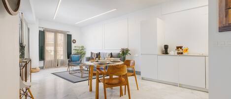 Uma zona de refeições moderna com uma mesa redonda, cadeiras de madeira e um sofá.