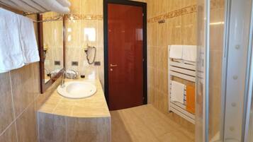 Ein Badezimmer mit Waschbecken, Spiegel, Handtuchhalter und Duschbereich.