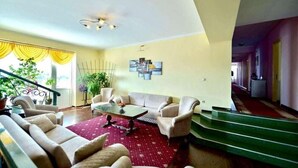 Ein Wohnzimmer mit einer Couch, Sesseln, einem Couchtisch und einer Treppe.