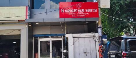 Un edificio con un letrero rojo que dice 'The Kashi Guest House / Home Stay' en Sarnath, Varanasi.