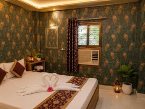 Habitación de hotel con cama, mesita de noche, espejo, ventana con cortinas y aire acondicionado de pared.