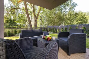 An outdoor patio area with wicker furniture and a table with fruit and a mug. - Air-conditioned Apartment with a Garden | 2 Bedrooms | Workspace (Gliwice)