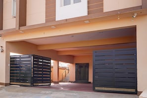 A building with a covered entrance, a staircase, and two large black gates.