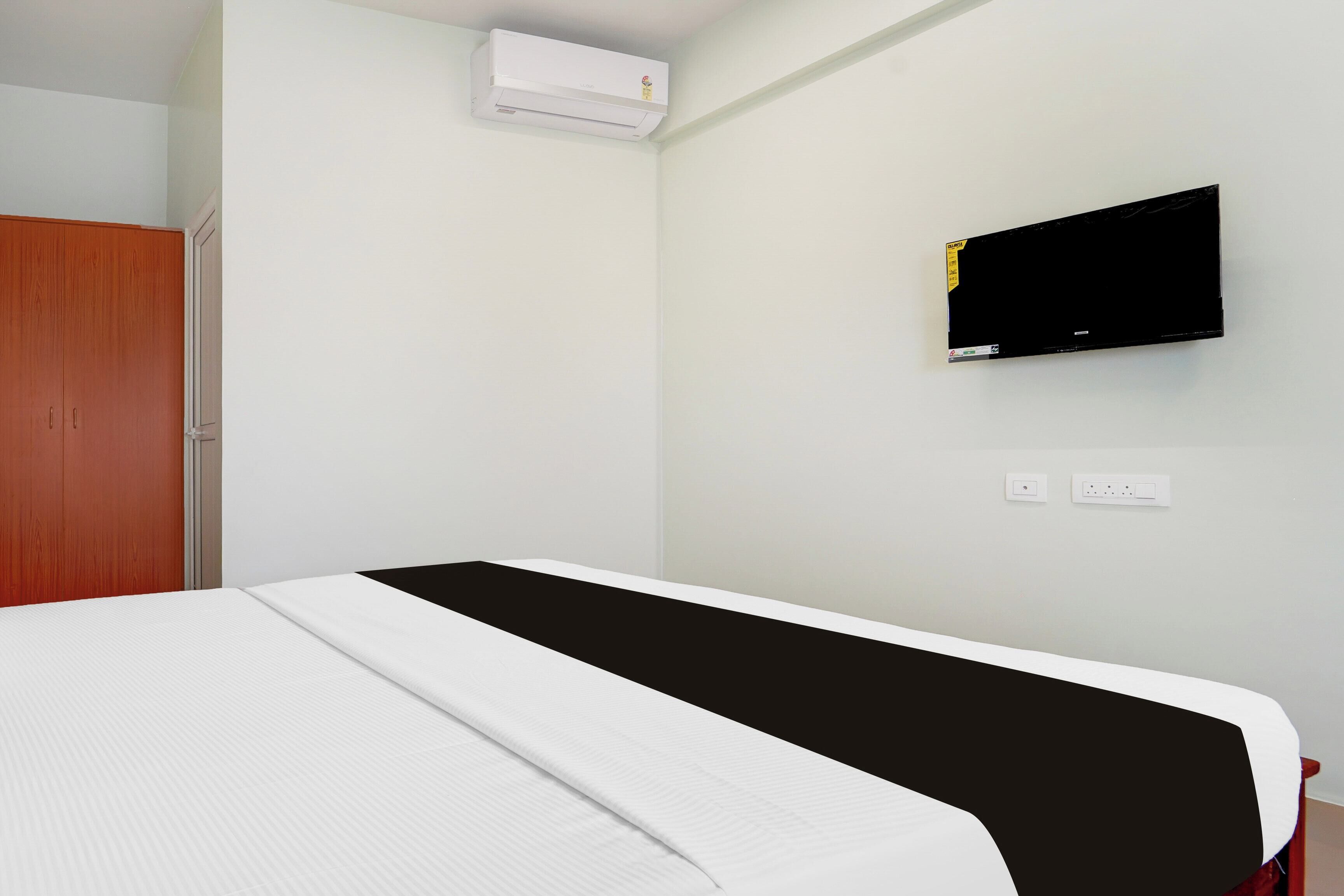 Una habitación con cama, aire acondicionado, televisión y un armario de madera.