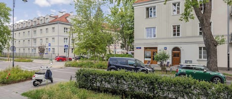 A street view with parked cars, a scooter, and a building with a sign that reads 'Schroeger'.