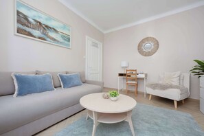 A living room with a sofa, a round table, a chair, a desk, and a plant. - Cozy Studio with a Workspace | Near the Metro (Warszawa)