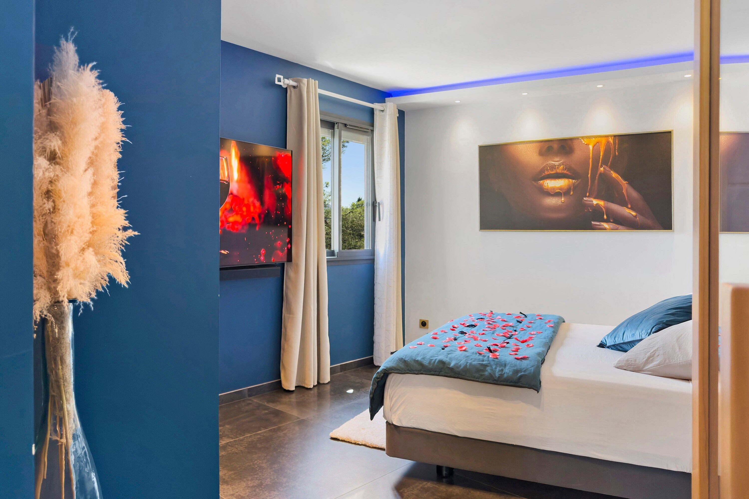 Een moderne slaapkamer met een bed, een groot raam en kunstwerken aan de wanden.