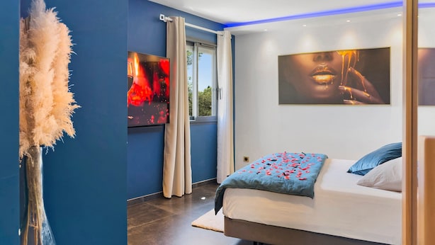 Un dormitorio moderno con cama, una ventana grande y obras de arte en las paredes.