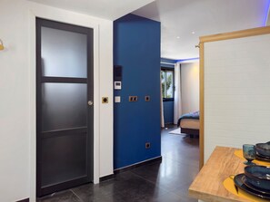 A modern hotel room with a dark door, a blue accent wall, a bed, and a table with plates and glasses. - Studio “La Parenthèse Dorée” with Mountain View, Wi-Fi and Air Conditioning (Les Pennes-Mirabeau)