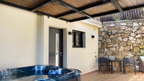 Un jacuzzi en un espacio exterior cubierto con paredes de piedra y una puerta.