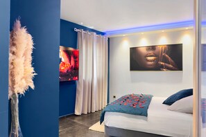 A modern bedroom with a bed, a wall-mounted TV, and a large abstract painting. - Studio “La Parenthèse Dorée” with Mountain View, Wi-Fi and Air Conditioning (Les Pennes-Mirabeau)
