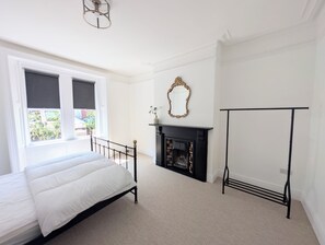 Ein Schlafzimmer mit Bett, Kamin, Spiegel und Fenster.