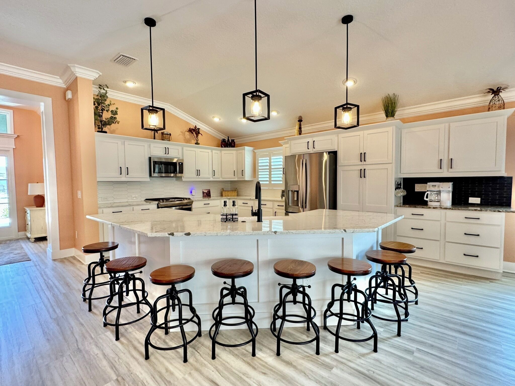 A spacious kitchen with a central island, bar stools, and modern appliances.