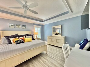 A bedroom with a bed, dresser, chair, ceiling fan, and artwork on the wall. - Coral Crest at Frogmore - 3/3 w/ 4-Seat Golf Cart in The Villages - Moultrie Creek (Moultrie Creek, The Villages)
